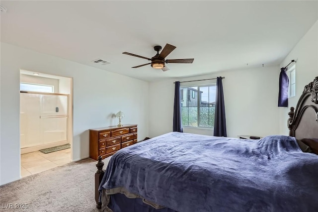 carpeted bedroom featuring tile patterned floors, visible vents, ensuite bathroom, and ceiling fan
