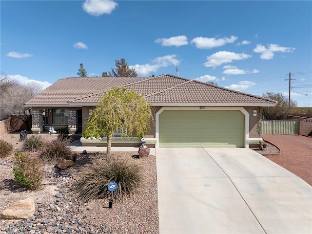 view of front facade featuring an attached garage, concrete driveway, a tile roof, fence, and stucco siding