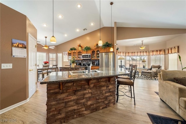kitchen featuring a breakfast bar, a wealth of natural light, brown cabinetry, stainless steel appliances, and a sink