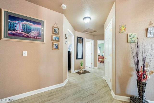 hall featuring light wood-type flooring and baseboards
