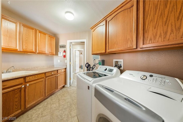 laundry area with a sink, washer and clothes dryer, cabinet space, and light floors
