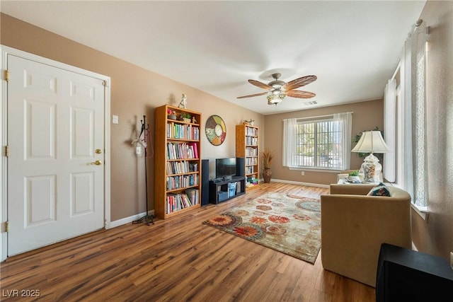 living area with wood finished floors, baseboards, and a ceiling fan