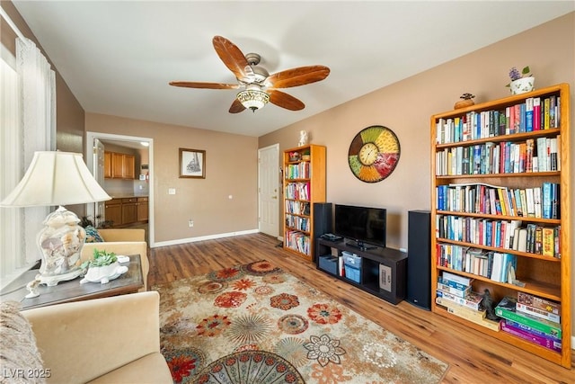 living area with ceiling fan, baseboards, and wood finished floors