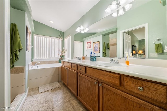 bathroom featuring a notable chandelier, a sink, double vanity, vaulted ceiling, and a garden tub