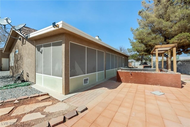 view of property exterior featuring a patio area, a sunroom, and stucco siding