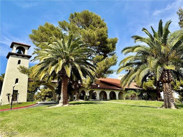 view of front of house with a front yard, a tiled roof, and stucco siding