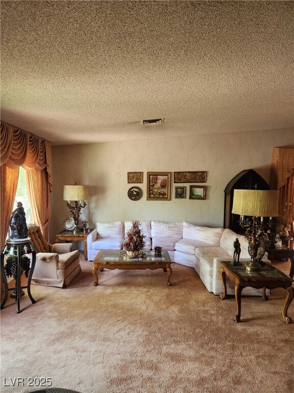 carpeted living area featuring visible vents and a textured ceiling
