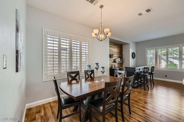 dining space featuring visible vents, baseboards, an inviting chandelier, and wood finished floors