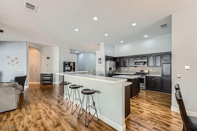 kitchen with visible vents, appliances with stainless steel finishes, a kitchen bar, and a spacious island