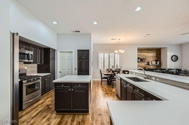 kitchen featuring visible vents, an inviting chandelier, a sink, stainless steel appliances, and decorative backsplash