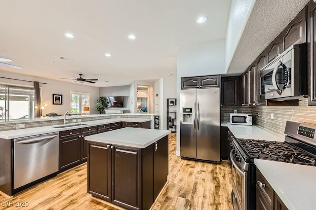 kitchen featuring light wood-style floors, a kitchen island, light countertops, a sink, and stainless steel appliances