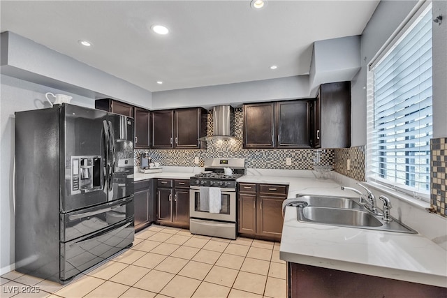 kitchen featuring a sink, dark brown cabinets, black refrigerator with ice dispenser, wall chimney range hood, and stainless steel gas range oven