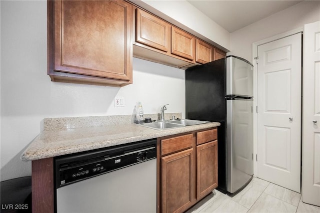 3135 S Mojave Rd Unit 241, Las Vegas, NV 89121 - kitchen featuring dishwasher, a sink, freestanding refrigerator, brown cabinetry, and marble finish floor