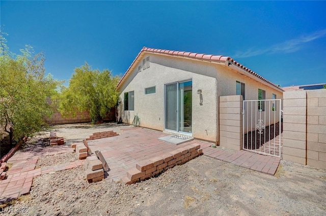 back of property with a tile roof, a patio, a fenced backyard, and stucco siding
