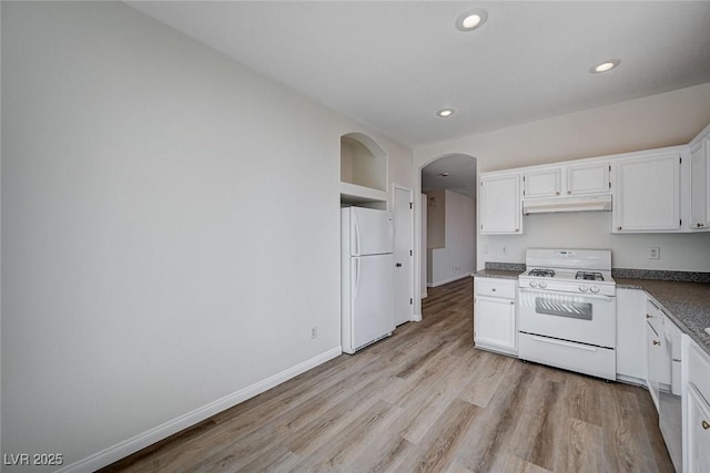 kitchen with under cabinet range hood, white appliances, arched walkways, and white cabinetry