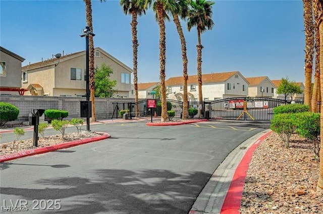 view of road featuring a residential view, a gated entry, curbs, and a gate