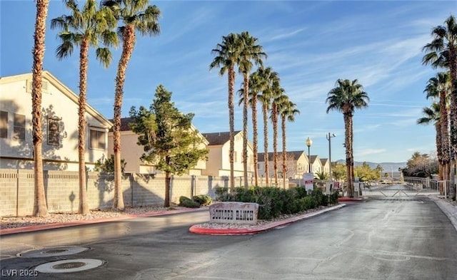 view of street featuring curbs, a residential view, a gated entry, and a gate