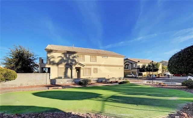 back of house with a tile roof, fence, and stucco siding