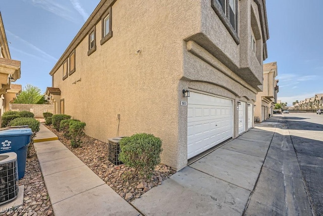 view of home's exterior featuring a garage, stucco siding, and central AC