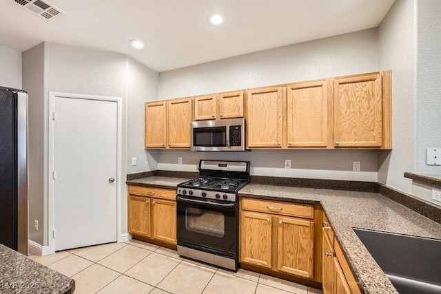 kitchen with dark countertops, visible vents, appliances with stainless steel finishes, and light tile patterned floors