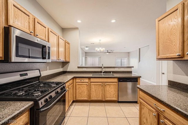 kitchen featuring an inviting chandelier, light tile patterned floors, a peninsula, stainless steel appliances, and a sink