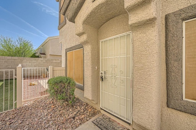 entrance to property with fence and stucco siding