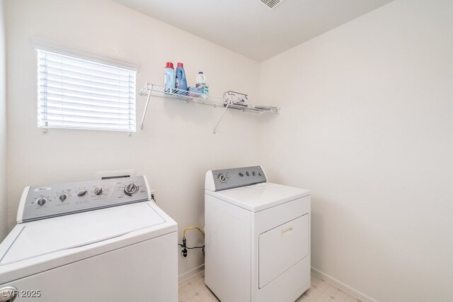 washroom with baseboards, separate washer and dryer, laundry area, and light floors