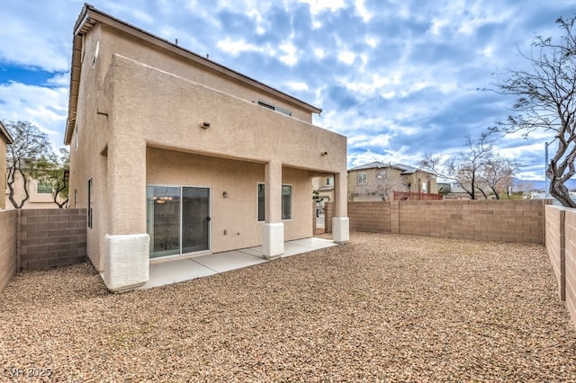 rear view of house with a fenced backyard, stucco siding, and a patio