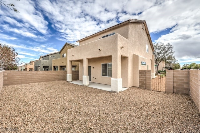 rear view of property featuring a fenced backyard, stucco siding, and a patio