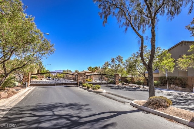view of street with a gated entry, a gate, and curbs