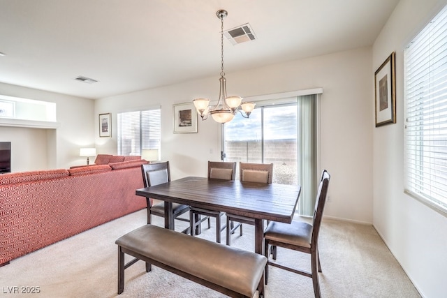 dining space featuring an inviting chandelier, light colored carpet, and visible vents