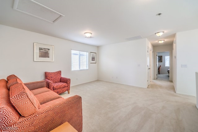 sitting room with attic access, baseboards, visible vents, and light carpet