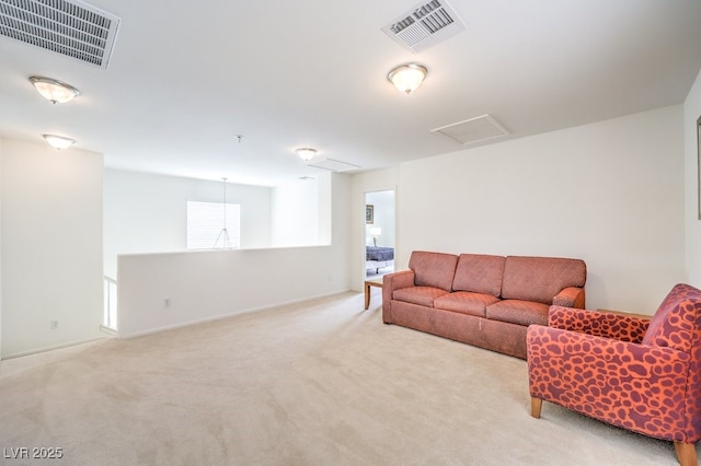 carpeted living area with baseboards, attic access, and visible vents