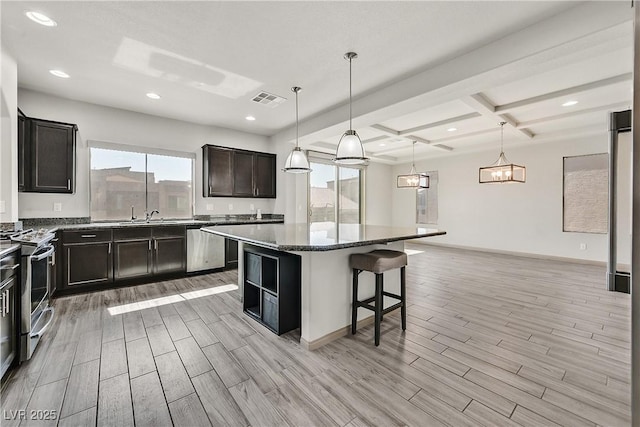 9830 Wild Coyote Ct, Las Vegas, NV 89141 - kitchen featuring stainless steel appliances, light wood finished floors, a kitchen breakfast bar, a kitchen island, and beamed ceiling