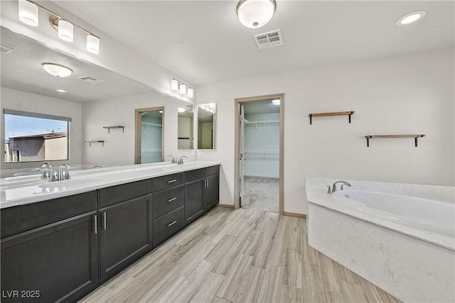9830 Wild Coyote Ct, Las Vegas, NV 89141 - full bathroom with a bath, double vanity, a walk in closet, wood finished floors, and baseboards