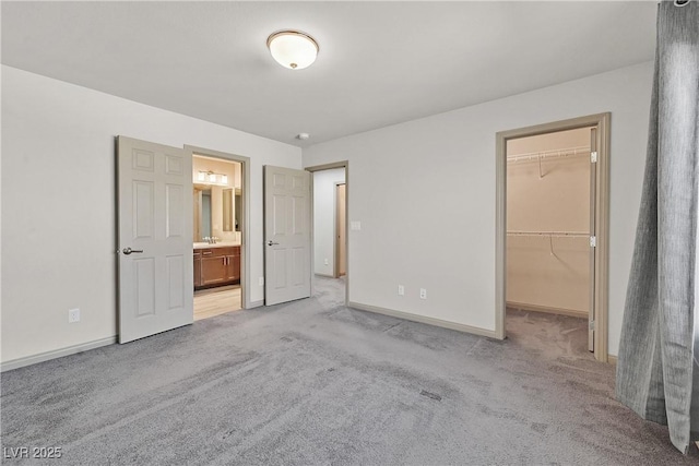 9830 Wild Coyote Ct, Las Vegas, NV 89141 - unfurnished bedroom with a spacious closet, light colored carpet, baseboards, and connected bathroom