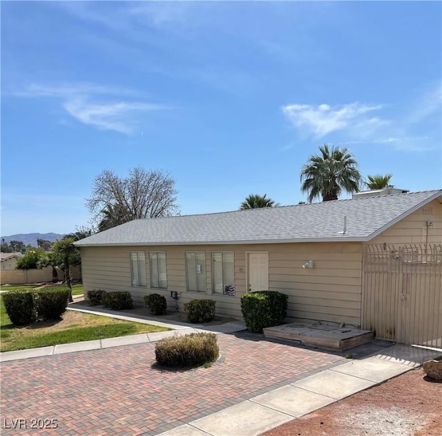 ranch-style house with roof with shingles and fence
