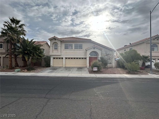 mediterranean / spanish-style house featuring a tile roof, stucco siding, an attached garage, and driveway