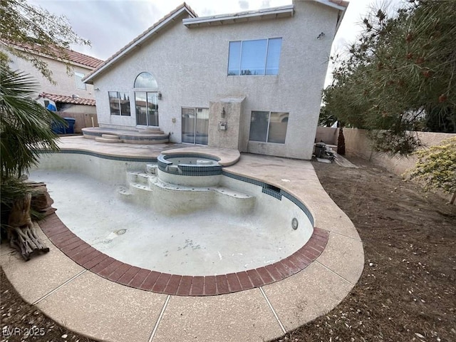 back of house with a tiled roof, a pool with connected hot tub, a patio, a fenced backyard, and stucco siding
