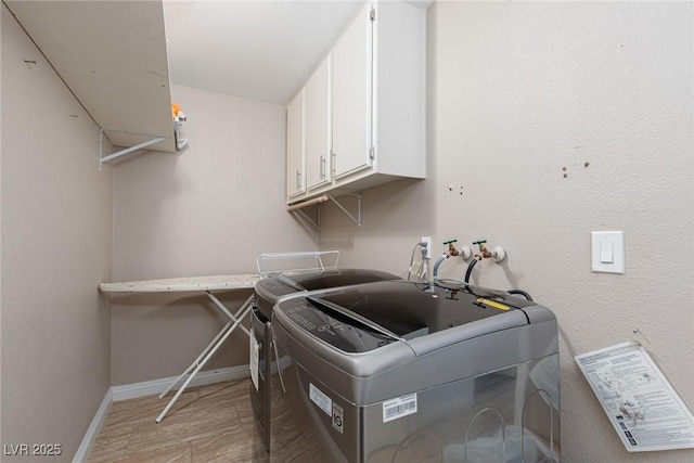 laundry area with washer and clothes dryer, cabinet space, light wood-type flooring, and baseboards