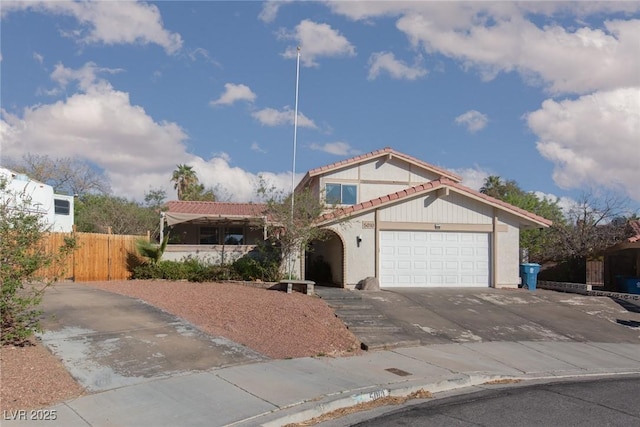 view of front of home with concrete driveway, fence, a tile roof, a garage, and stucco siding