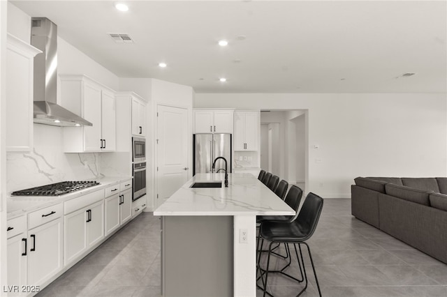 31 Autumn Palm Ave, Henderson, NV 89011 - kitchen featuring wall chimney exhaust hood, stainless steel appliances, a sink, a breakfast bar, and decorative backsplash