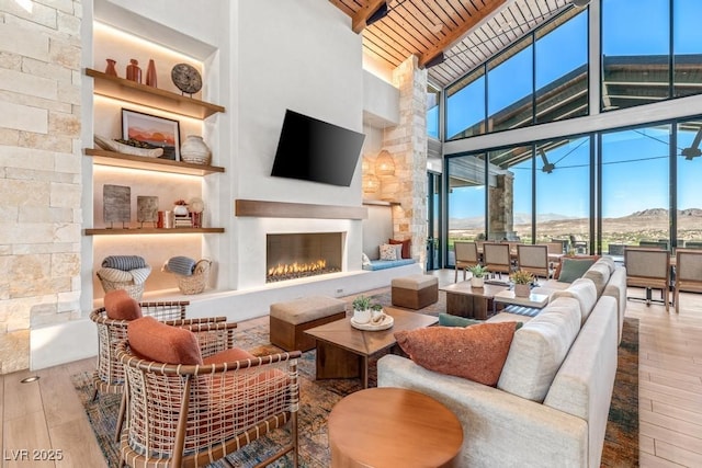 31 Autumn Palm Ave, Henderson, NV 89011 - living room with high vaulted ceiling, wood-type flooring, a warm lit fireplace, beamed ceiling, and floor to ceiling windows