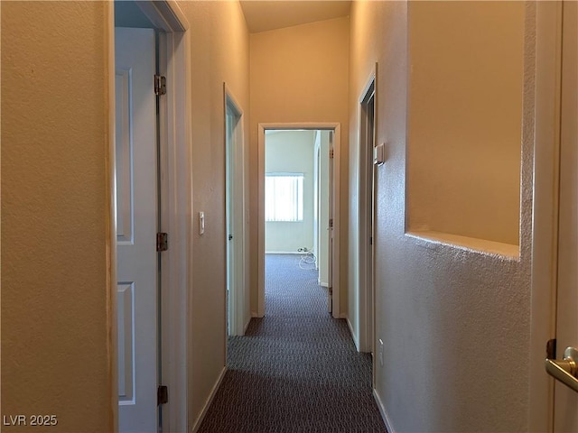 6080 Golden Corral Trl Unit 103, Henderson, NV 89011 - hallway featuring dark carpet, a textured wall, and baseboards