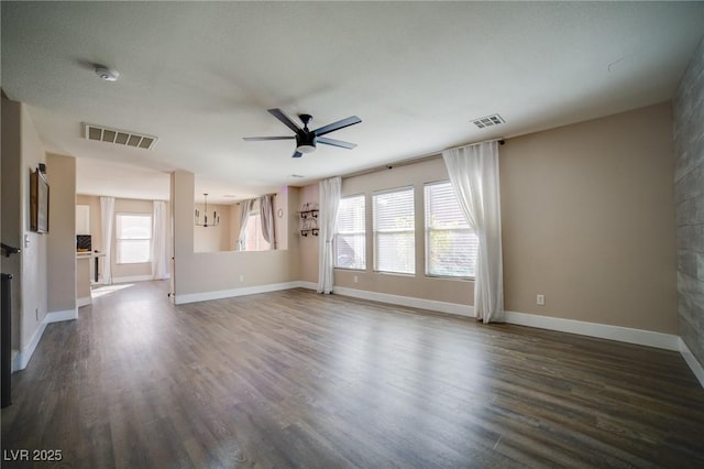 unfurnished living room with dark wood-style flooring, baseboards, ceiling fan, and visible vents