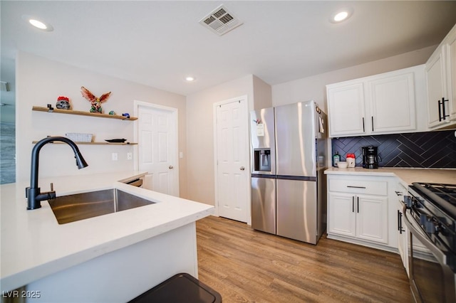 kitchen featuring light countertops, a sink, appliances with stainless steel finishes, light wood-type flooring, and visible vents