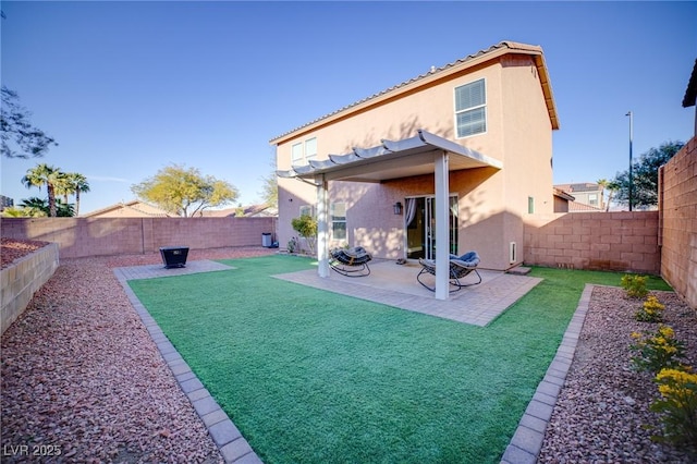 rear view of house featuring a fenced backyard, a lawn, stucco siding, and a patio area
