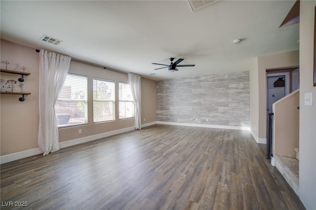 interior space with ceiling fan, wood finished floors, an accent wall, and visible vents