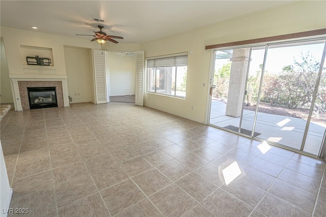 unfurnished living room with light tile patterned floors, a ceiling fan, a tile fireplace, and visible vents