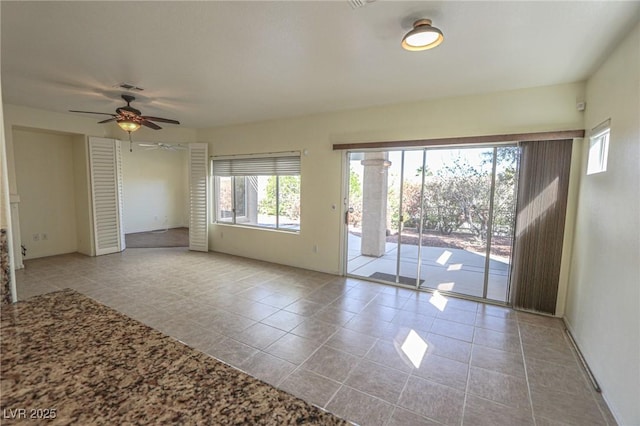 tiled spare room with ceiling fan and visible vents